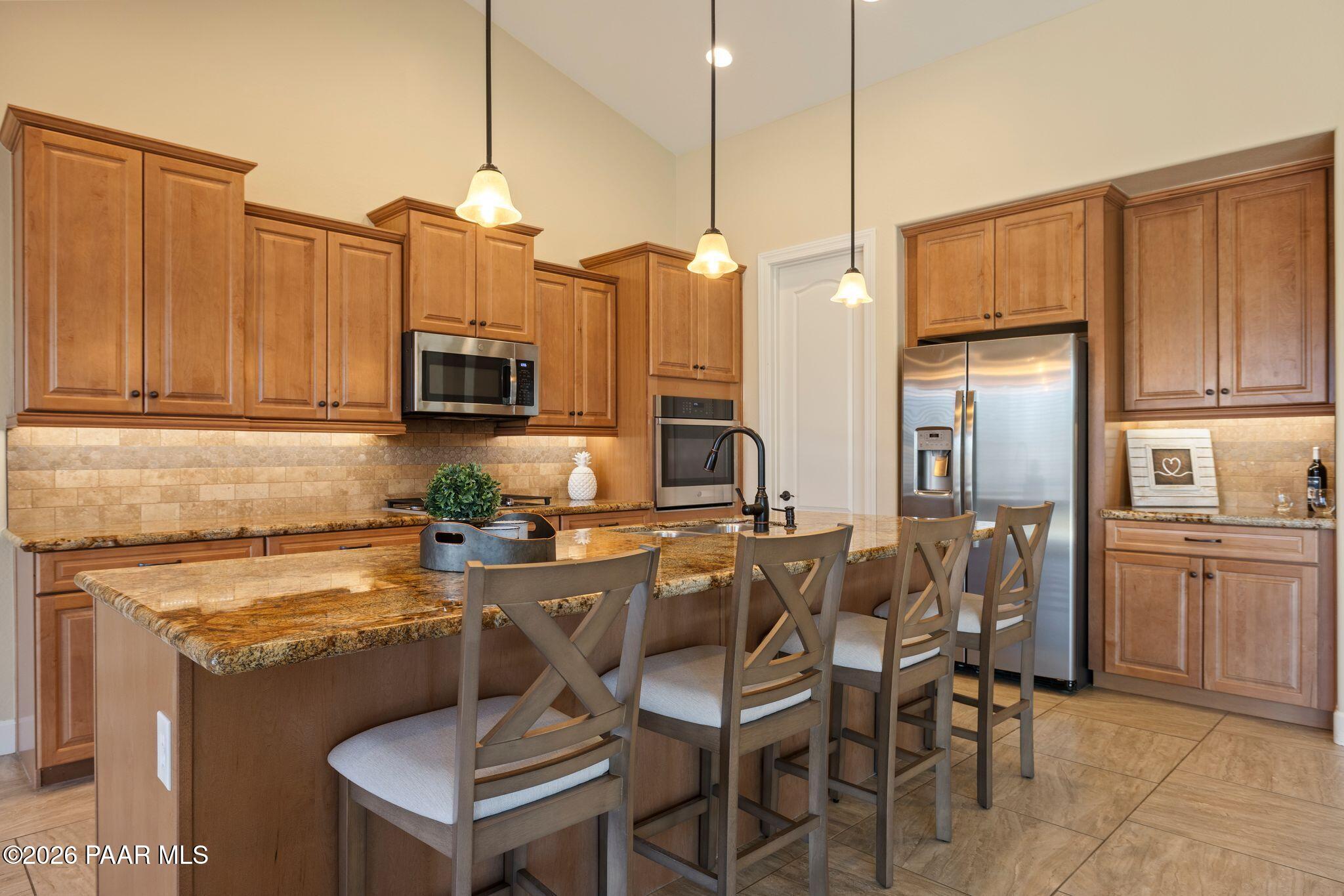4850 West Three Forks Road Prescott, AZ 86305 - Photo 14 of 69 a kitchen with stainless steel appliances granite countertop a stove top oven a refrigerator a sink and chairs
