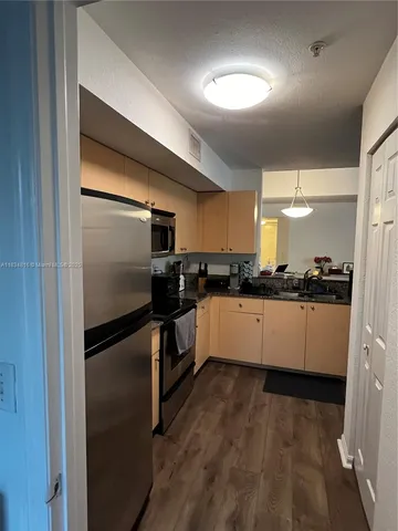 a kitchen with granite countertop a refrigerator and a stove top oven