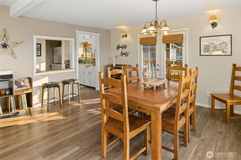 a dining room with wooden floor a glass table and chairs