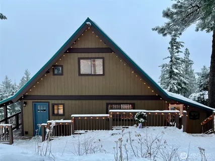 a front view of a house with large trees