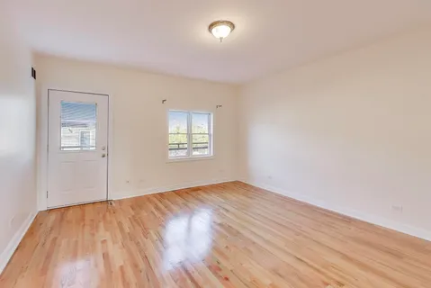 a view of an empty room with wooden floor and entryway