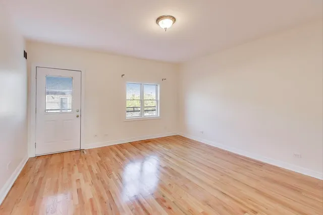a view of an empty room with wooden floor and entryway