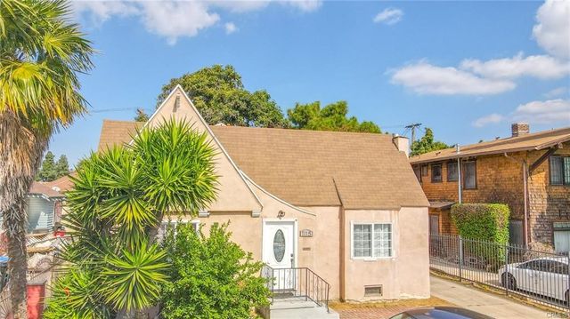 a view of a house with a palm tree next to a yard