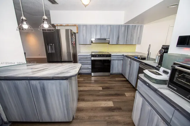 a kitchen with kitchen island a counter space a sink appliances and cabinets