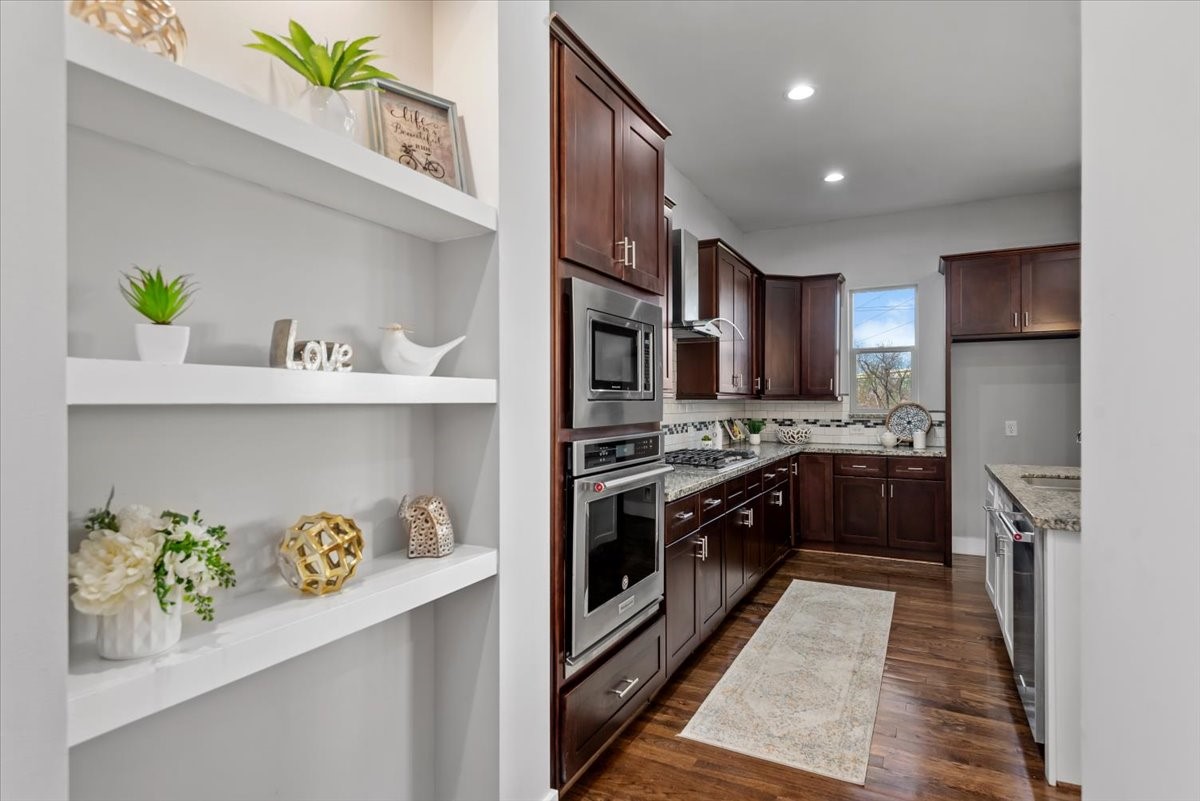 1005 Bingham Street, Unit 5 Houston, TX 77007 - Photo 3 of 50 The open shelving adds a decorative touch, and the space is well-lit with recessed lighting. A window above the sink provides natural light, enhancing the warm and inviting ambiance.