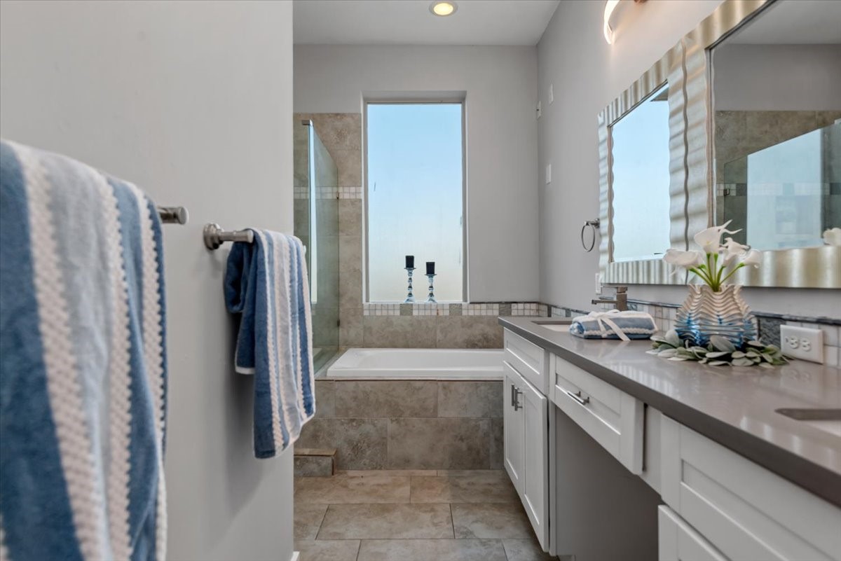 1005 Bingham Street, Unit 5 Houston, TX 77007 - Photo 37 of 50 This bathroom features a modern design with a sleek vanity, a large mirror, and ample natural light. It includes a tiled bathtub, and stylish accents, creating a serene and inviting space.