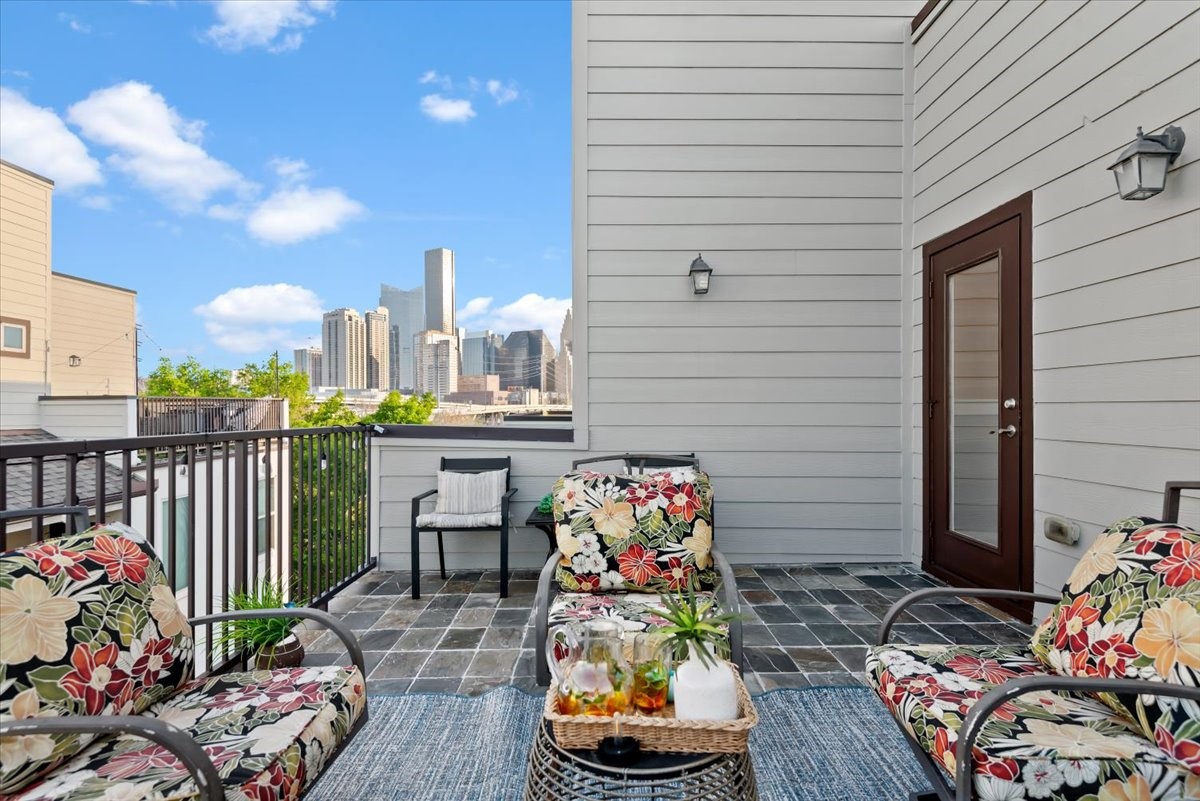 1005 Bingham Street, Unit 5 Houston, TX 77007 - Photo 40 of 50 This photo showcases a cozy rooftop patio with a stunning view of the city skyline. The space is inviting, perfect for relaxation or entertaining, and features modern outdoor lighting and a glass door entry.