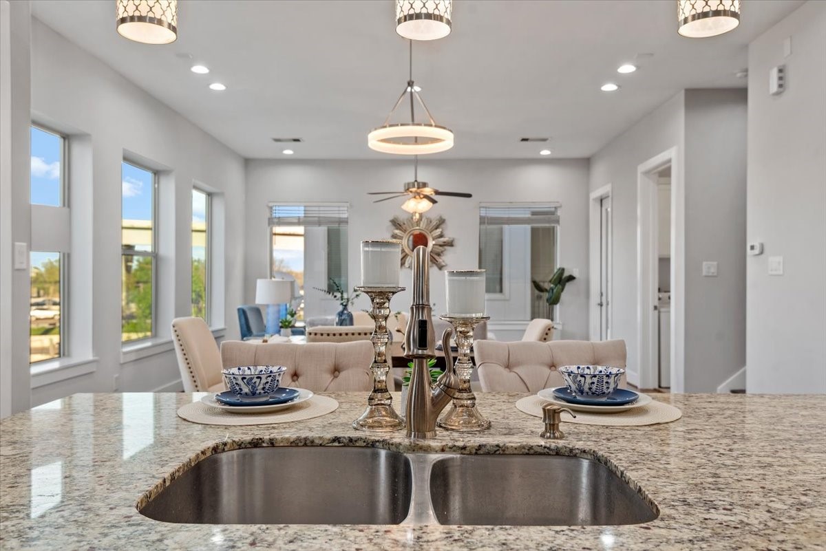 1005 Bingham Street, Unit 5 Houston, TX 77007 - Photo 5 of 50 This photo showcases a modern, open-concept living and dining area with abundant natural light. The space features elegant lighting fixtures, a granite kitchen island with a sink, and stylish decor, creating a welcoming and sophisticated ambiance.