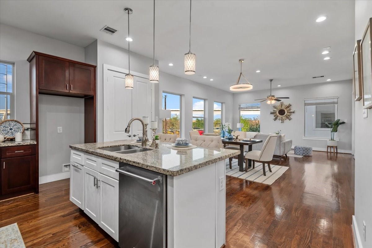 1005 Bingham Street, Unit 5 Houston, TX 77007 - Photo 8 of 50 This photo highlights a bright, open-concept kitchen and living area with rich hardwood floors. The kitchen features a central island, modern pendant lighting, and sleek stainless steel appliances. The adjoining dining and living spaces are filled with natural light from multiple windows, creating a warm, welcoming, and spacious atmosphere.
