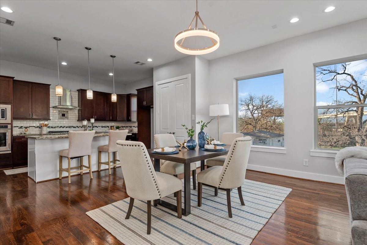 1005 Bingham Street, Unit 5 Houston, TX 77007 - Photo 9 of 50 This photo showcases a modern open-concept kitchen and dining area with hardwood floors. The dining area is cozy and bright, with large windows offering outdoor views.