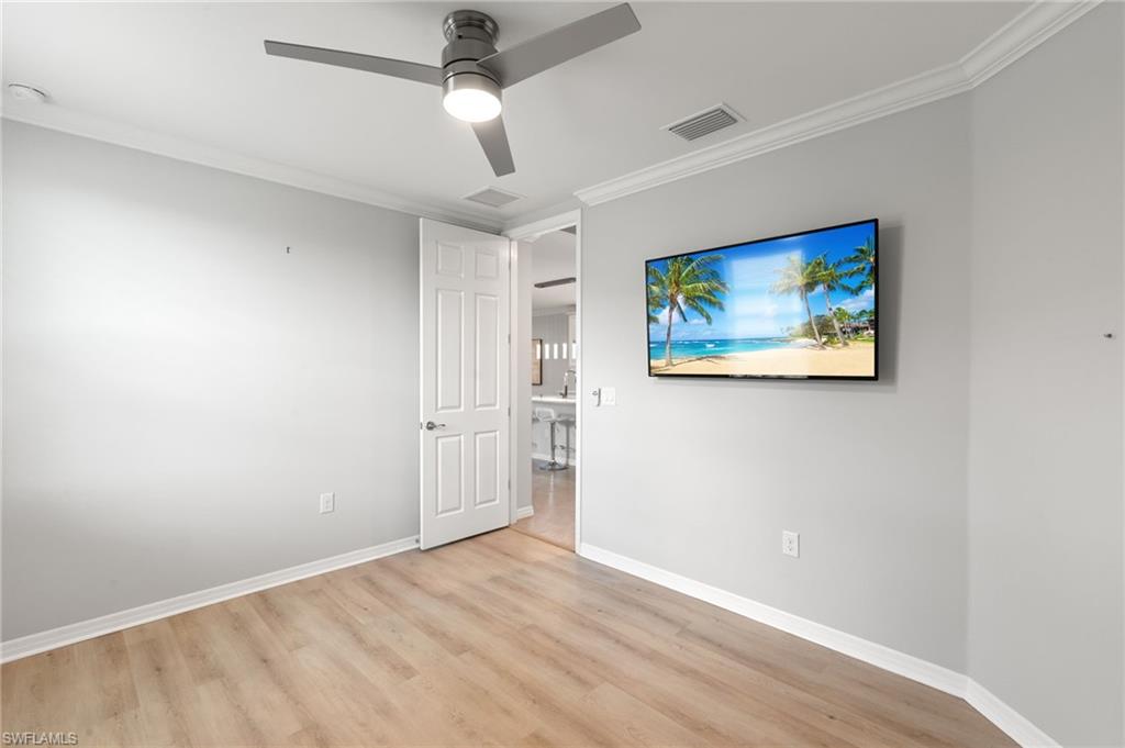 14618 Edgewater Circle Naples, FL 34114 - Photo 24 of 47 an empty room with wooden floor ceiling fan and windows
