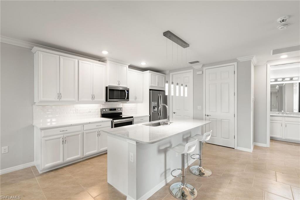 14618 Edgewater Circle Naples, FL 34114 - Photo 4 of 47 a kitchen with a sink stainless steel appliances and white cabinets