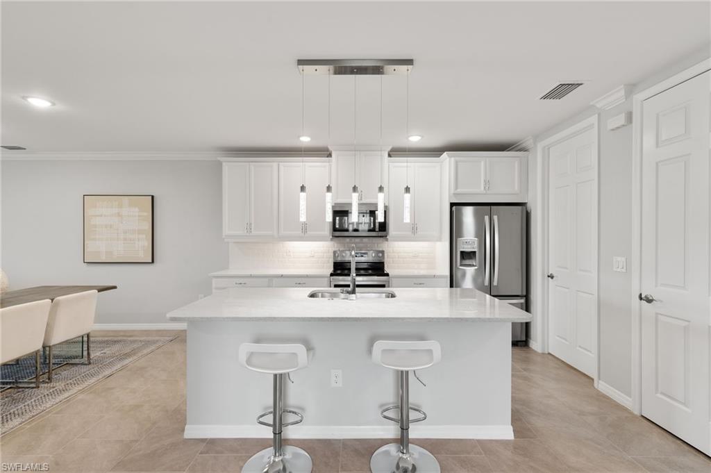 14618 Edgewater Circle Naples, FL 34114 - Photo 6 of 47 a kitchen with kitchen island a appliances a counter space and a refrigerator