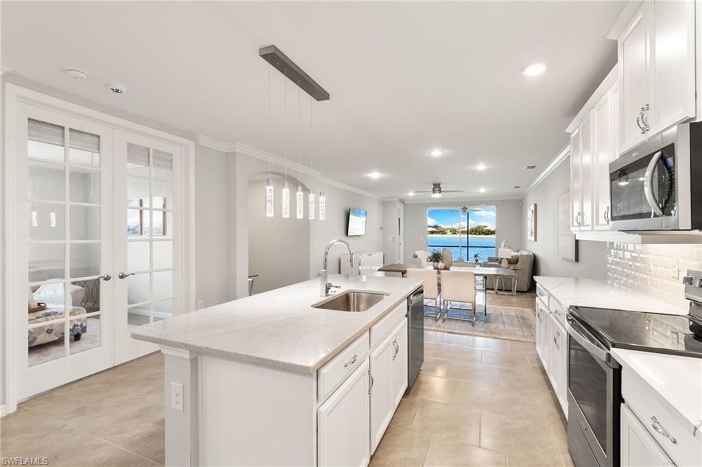 14618 Edgewater Circle Naples, FL 34114 - Photo 7 of 47 a large kitchen with kitchen island a sink a stove a chimney a dining table and chairs