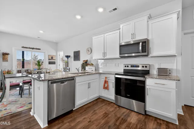 a dining room with furniture a rug and kitchen view