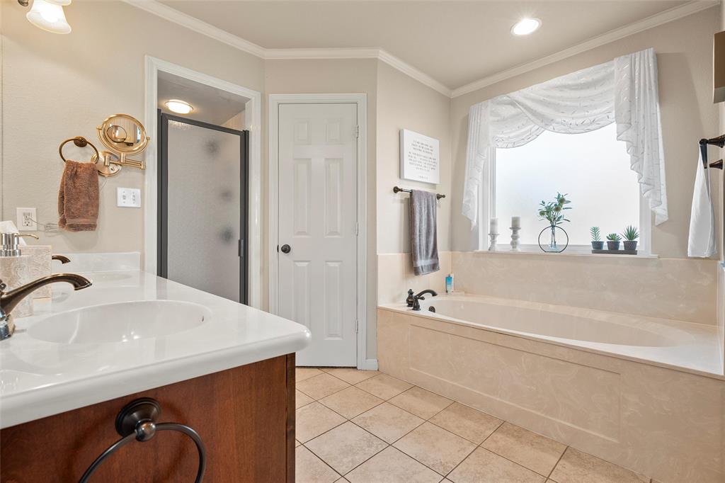 142 Phillip Circle Hewitt, TX 76643 - Photo 13 of 24 Full bath with double vanity, a shower stall, a garden tub, light tile patterned floors, and crown molding