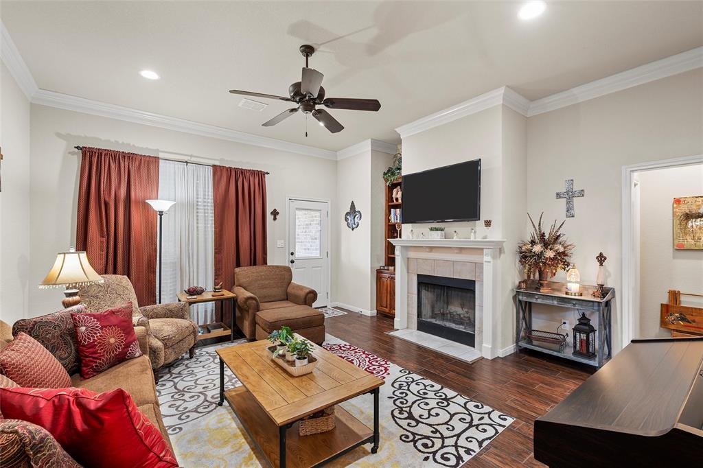 142 Phillip Circle Hewitt, TX 76643 - Photo 4 of 24 Living room featuring a tiled fireplace, dark wood-style floors, ornamental molding, and a ceiling fan