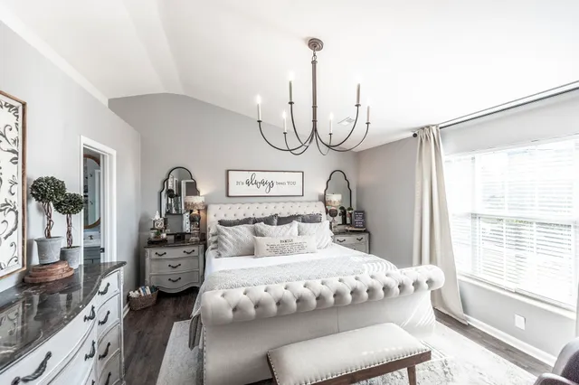 a bedroom with a bed a chandelier and dresser