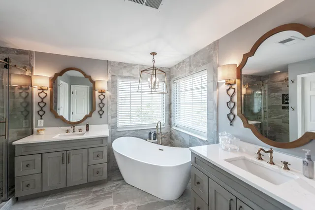 a bathroom with a double vanity sink mirror and bathtub