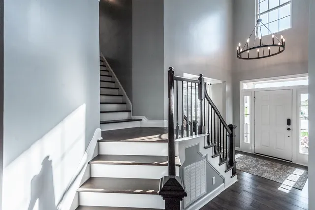 a view of staircase with wooden floor and pendant lights