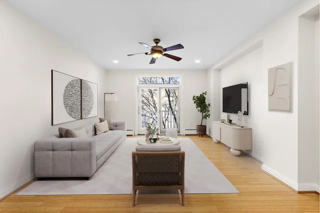 a living room with furniture a flat screen tv and a window