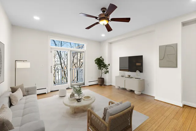 a living room with furniture a flat screen tv and a window