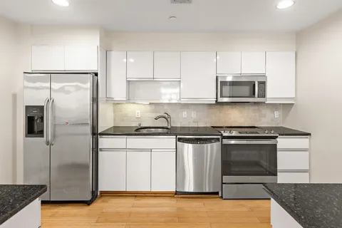 a kitchen with stainless steel appliances granite countertop a stove a refrigerator and a microwave