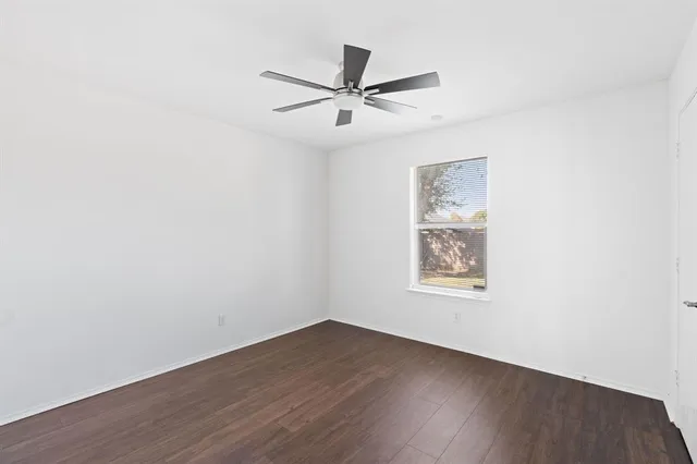 an empty room with wooden floor ceiling fan and windows
