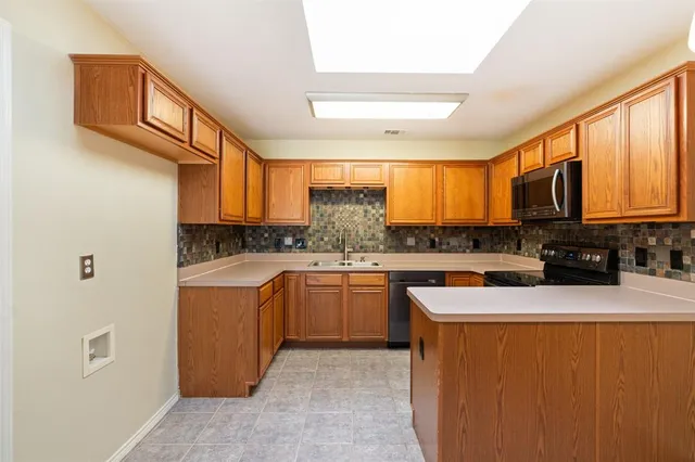 a kitchen with stainless steel appliances granite countertop a sink a stove a refrigerator cabinets and a window