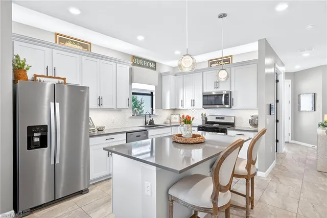 a kitchen with a refrigerator a stove a sink and chairs