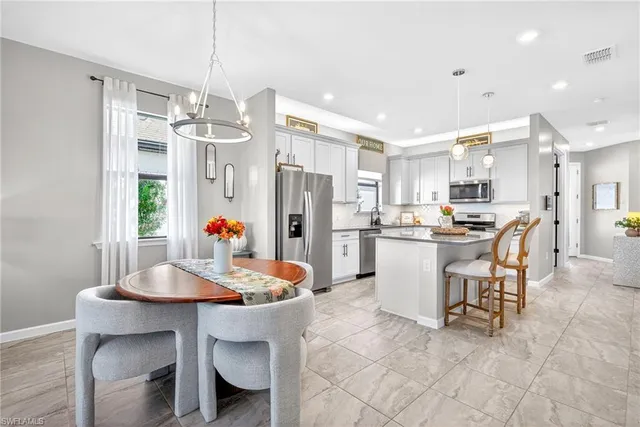 a kitchen with a dining table chairs stainless steel appliances and cabinets