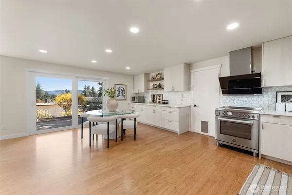 a kitchen with stainless steel appliances kitchen island granite countertop a stove top oven a sink a dining table and chairs with wooden floor