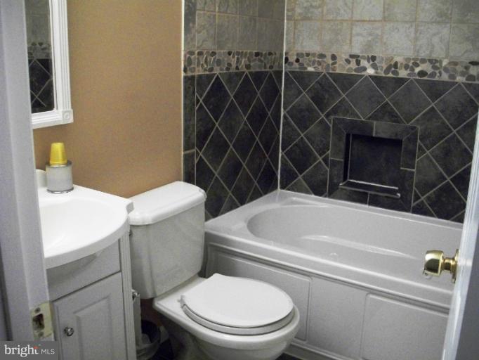 897 Beech Tree Road Severn, MD 21144 - Photo 25 of 30 a white toilet sitting next to a bathroom sink and vanity