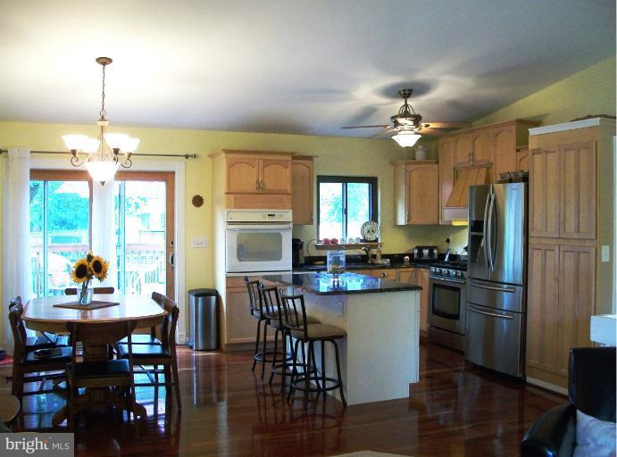 897 Beech Tree Road Severn, MD 21144 - Photo 4 of 30 a kitchen with stainless steel appliances a dining table chairs stove refrigerator and cabinets
