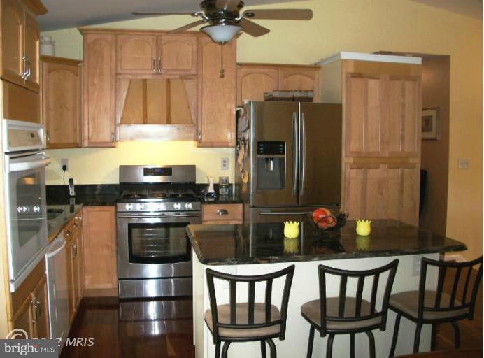 897 Beech Tree Road Severn, MD 21144 - Photo 8 of 30 a kitchen with stainless steel appliances wooden floor dining table and chairs
