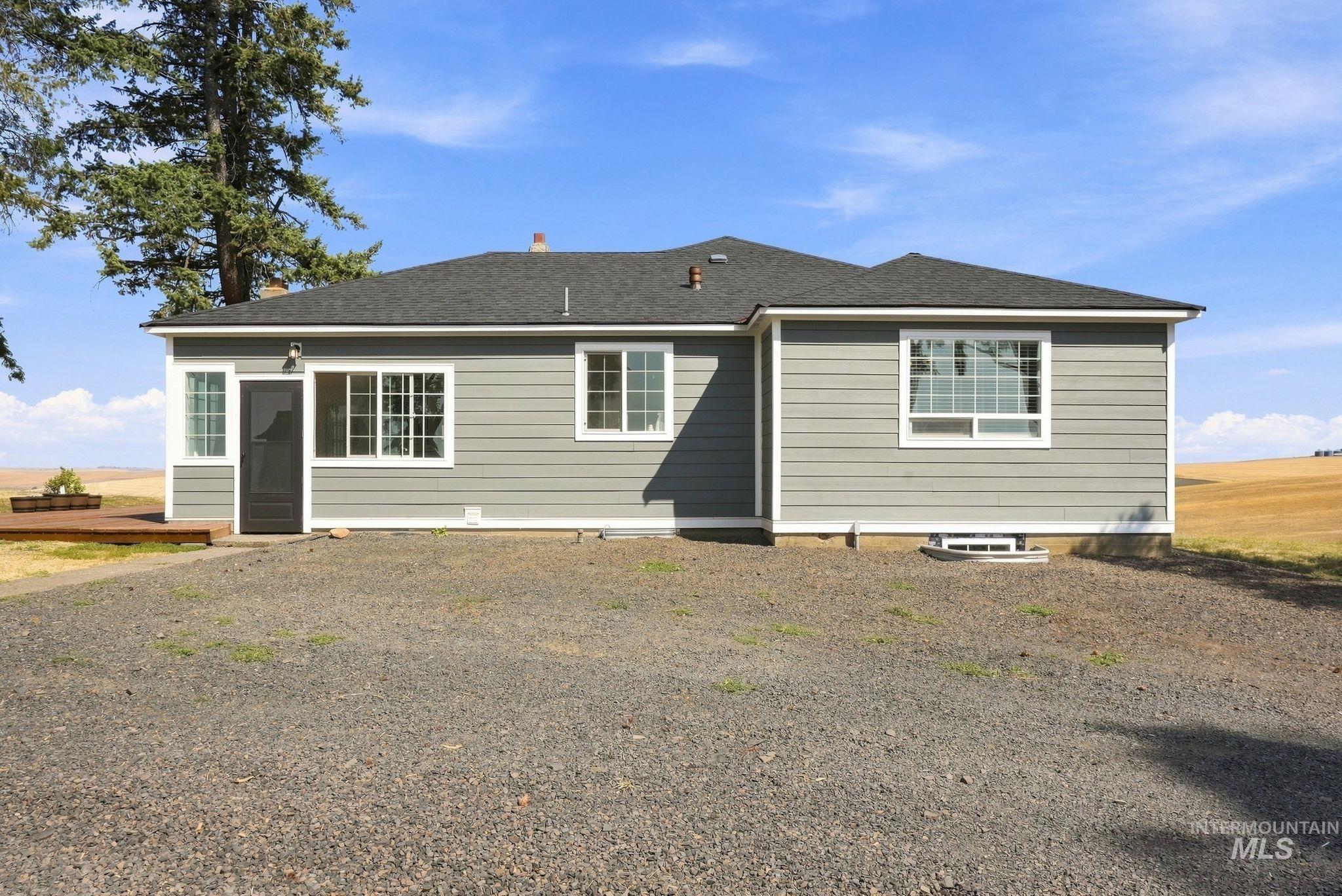 16078 Hoffman Road Kendrick, ID 83537 - Photo 27 of 47 Gray horizontal siding exterior with a dark roof, white trim windows, and a dark entry door
