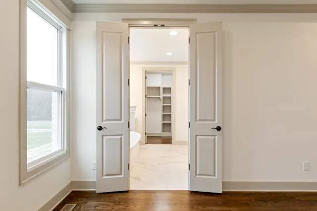 a view of an empty room with a window and a kitchen