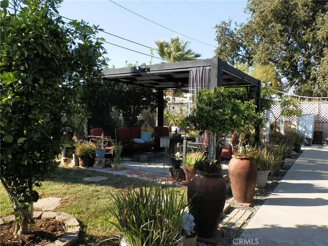 a view of a patio with table and chairs potted plants and large tree