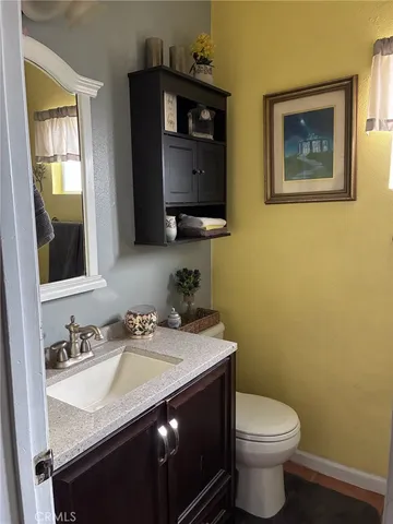 a bathroom with a granite countertop toilet sink and mirror