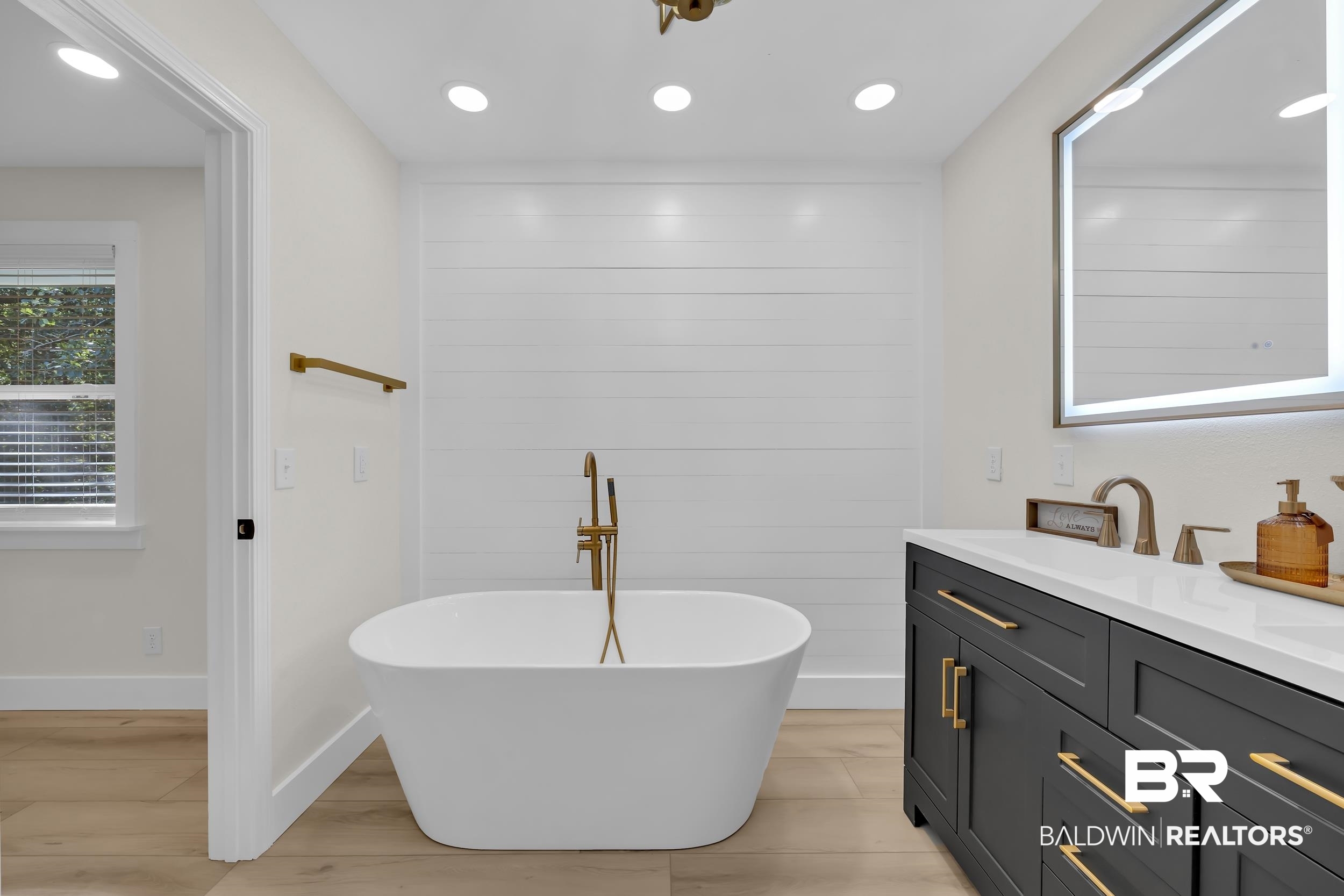 8170 Wilmer Georgetown Road Wilmer, AL 36587 - Photo 15 of 31 Freestanding oval bathtub with a floor-mounted gold-tone faucet, set against a shiplap accent wall