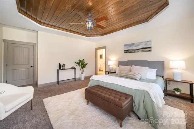 a spacious bedroom with a bed a chandelier and couches
