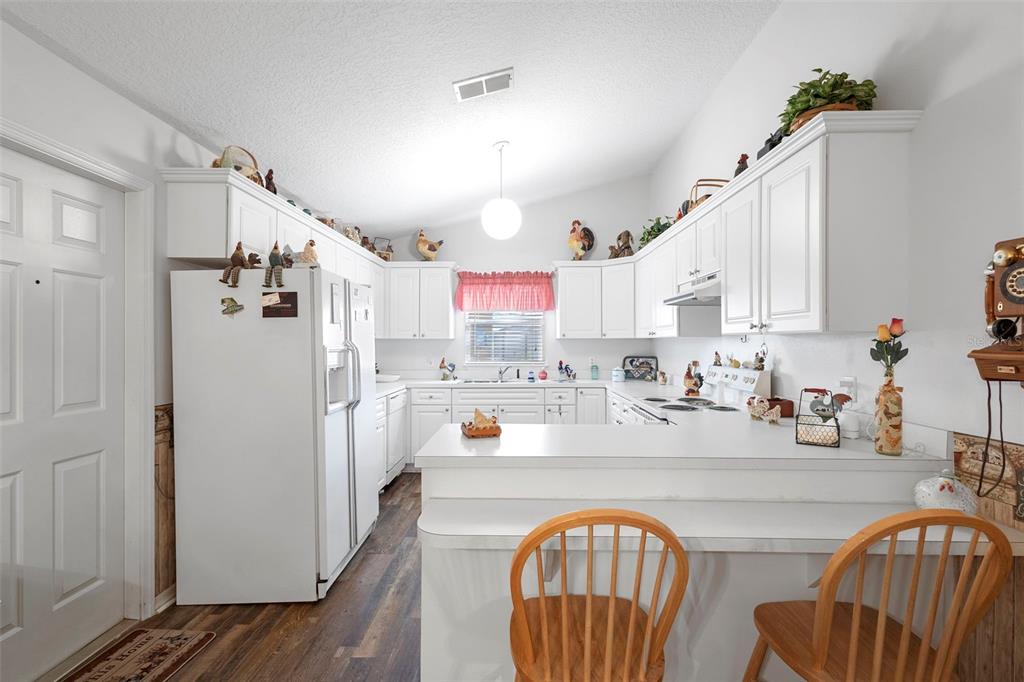 10320 Bumblebee Lane Leesburg, FL 34788 - Photo 12 of 49 a kitchen with stainless steel appliances granite countertop a refrigerator a stove a sink dishwasher with a dining table and chairs