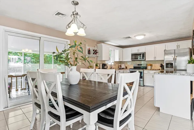 a view of a dining room with furniture a chandelier and large windows