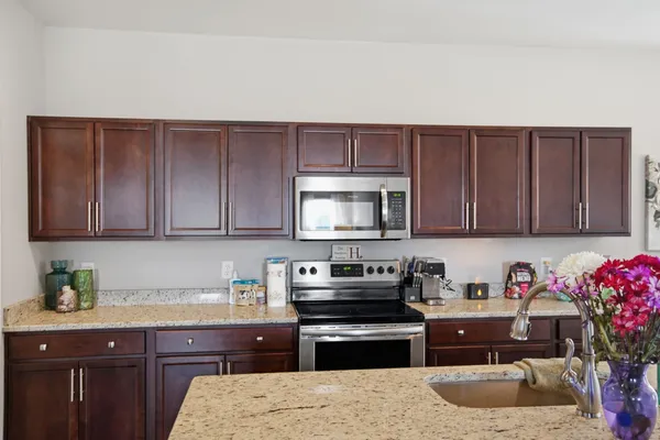a kitchen with granite countertop a sink dishwasher stove and cabinets with wooden floor