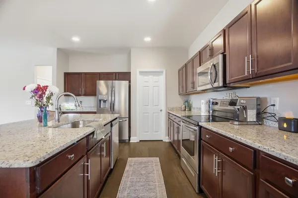 a kitchen with granite countertop stainless steel appliances a sink dishwasher a refrigerator a stove top oven and a counter space