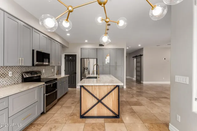 a kitchen with stainless steel appliances granite countertop a sink a stove top oven a counter space and cabinets