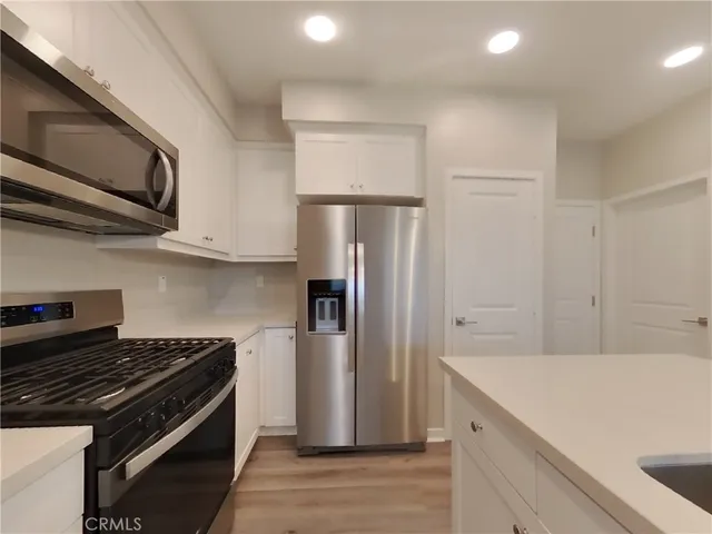 a kitchen with stainless steel appliances granite countertop a refrigerator and a stove top oven