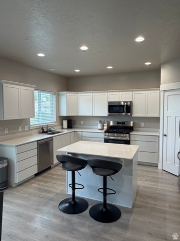 437 North 650 E Street Springville, UT 84663 - Photo 4 of 11 Modern kitchen featuring an island with stone countertops, white shaker cabinetry, stainless steel appliances, and wood-finish flooring