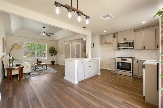 a kitchen with stainless steel appliances kitchen island wooden floors and white cabinets