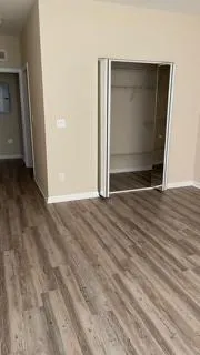 a view of an empty room with wooden floor and door